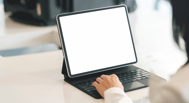 Cropped shot of woman hand typing on tablet keyboard while sitting at the table, blank screen for graphic design.