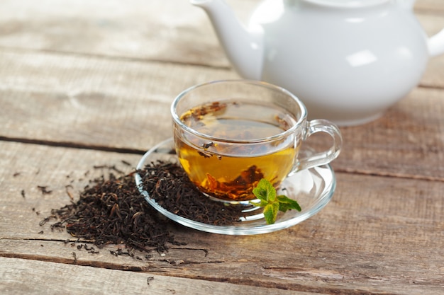 Cup of black tea with mint leaves on a wooden table