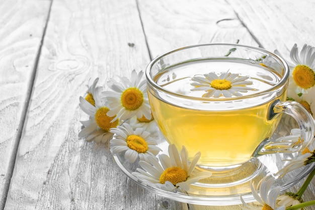 Photo cup of tea with chamomile flowers on rustic wooden background