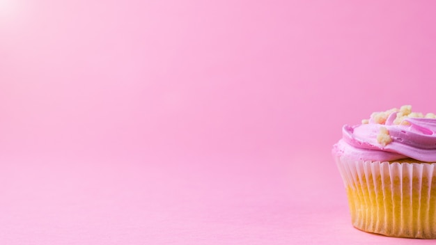 Cupcake with pink cream on a solid pink surface