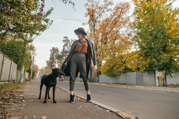 Curly lady in a hat walks a dog on the village street