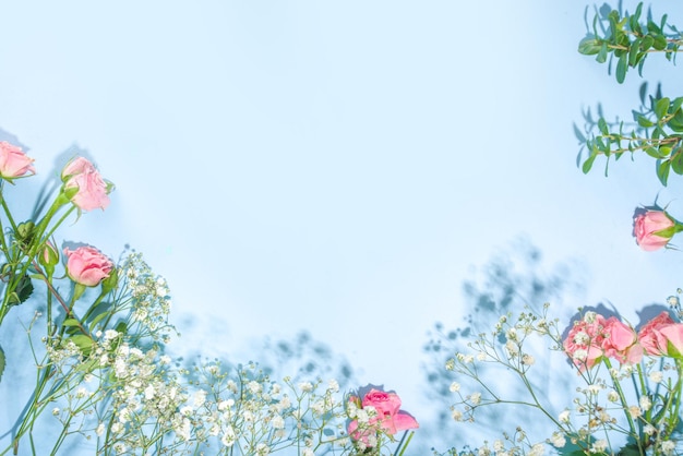 Photo cute spring flatlay with flowers and green spring leaves, high-colored bright sunny blue background, top view frame