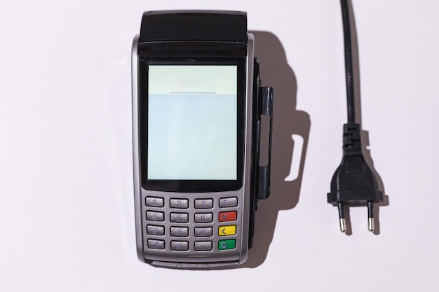 Photo dataphone to pay with a credit card next to an electric cable on a white background concept of electricity rising prices impoverishment and economy