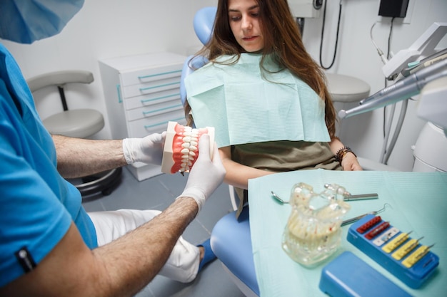 Dentist showing teeth cleaning technique to client.