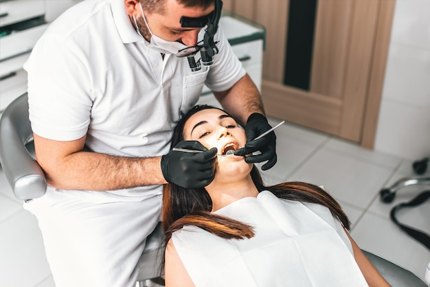 Dentist working in dental clinic with female patient in the chair