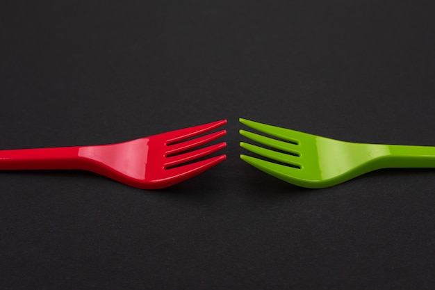 Disposable red and green plastic forks isolated on background