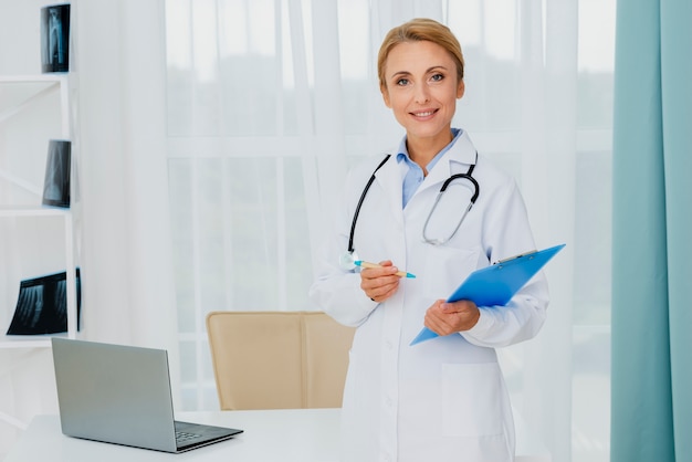 Doctor holding clipboard looking at camera