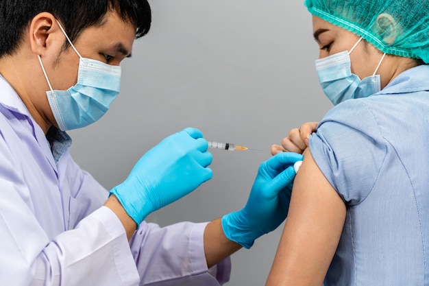 Photo doctor holding syringe and using cotton before make injection to nurse or medical professionals in a mask. covid-19 or coronavirus vaccine