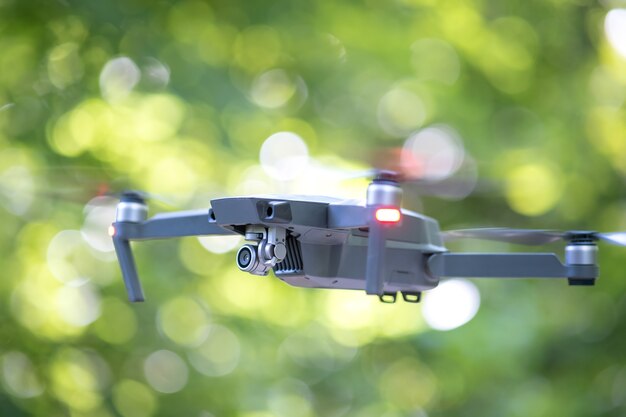 Drone aircraft with blurred fast rotating propellers and video camera flying in air