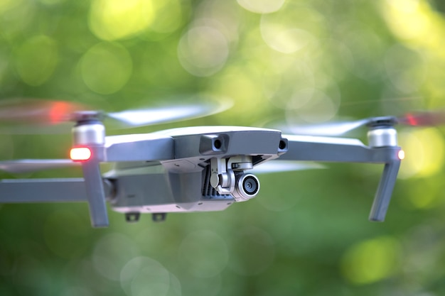 Drone aircraft with blurred fast rotating propellers and video camera flying in air.