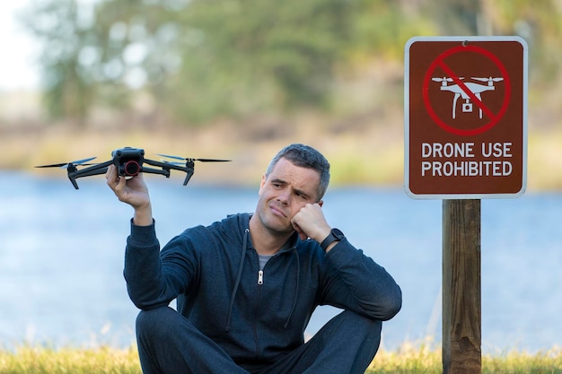 Drone operator is disappointed because he isn't allowed to fly his quadcopter in national park no drone area Man is unable to use his UAV near restriction notice sign Airspace use regulations