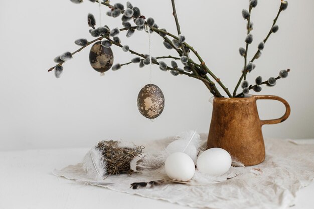 Photo easter rustic still life natural eggs feathers nest willow branches in vase on aged wooden table