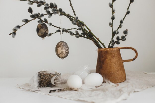 Photo easter rustic still life natural eggs feathers nest willow branches in vase on aged wooden table