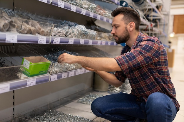 Een man in een ijzerhandel koopt een groot deel van een zelftappende schroef