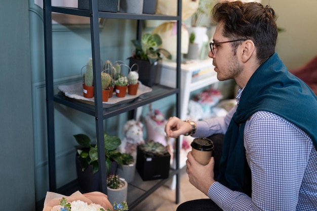 Een man kijkt naar de planken in een bloemenwinkel terwijl hij wacht tot er een boeket voor hem wordt klaargemaakt