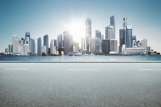 Empty highway asphalt roadside with modern city skyline and sea background .