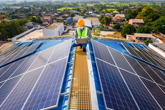 Photo engineers use a laptop computer to examine the solar panels on the roof of a house where the solar panels are installed using solar energy.