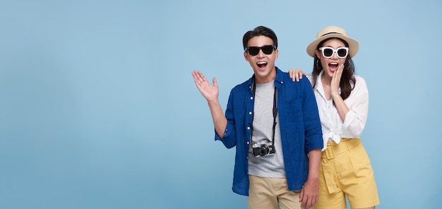 Photo excited asian couple tourist dressed in summer clothes to travel on holidays isolated on blue copy space background