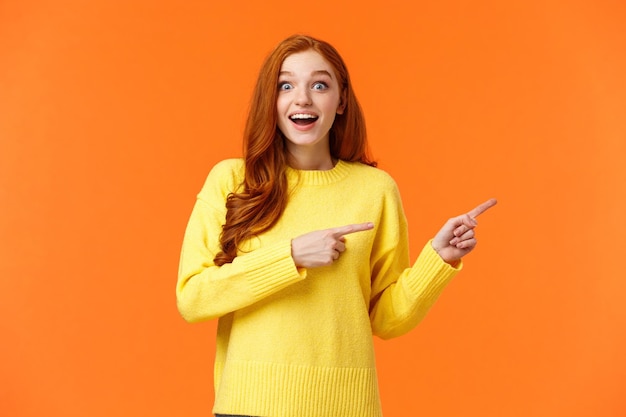 Photo excited surprised and fascinated goodlooking redhead hipster girl in yellow sweater