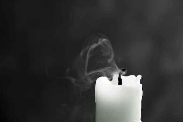 Photo extinct white candle with spectacular, abstract smoke on a black background, black and white photo, close-up, frozen smoke.