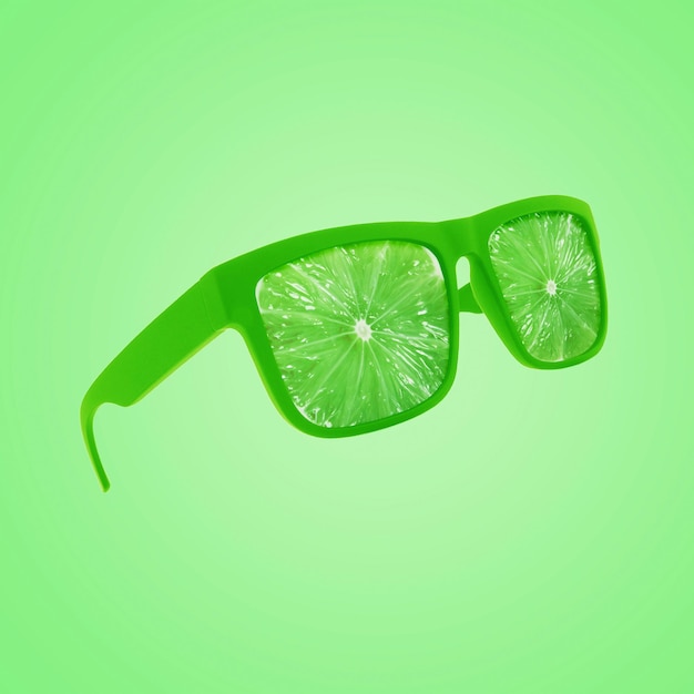 Fashion green sunglasses with juicy fresh lime floating on a green pastel background creative idea Vitamins a concept