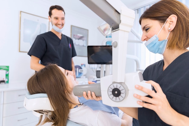 Female dentist with x-ray machine scanning patient's teeth at dental clinic