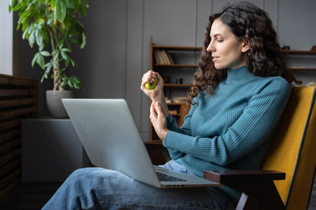 Female employee exercising with stress relieving silicone grip ring relaxing from computer work