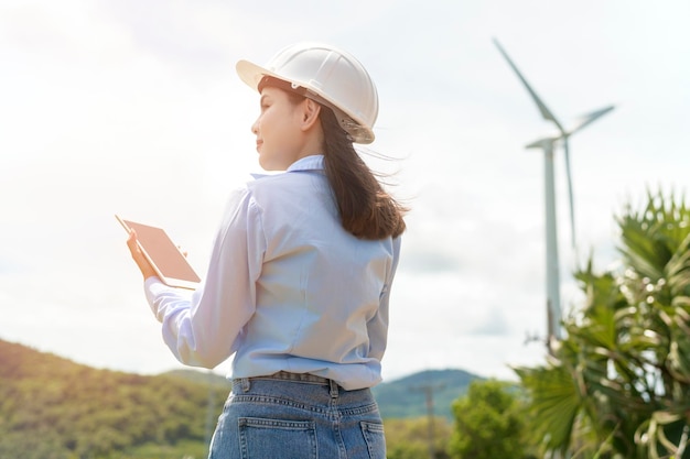 Photo female engineer working on the seaside wearing a protective helmet over electrical turbines