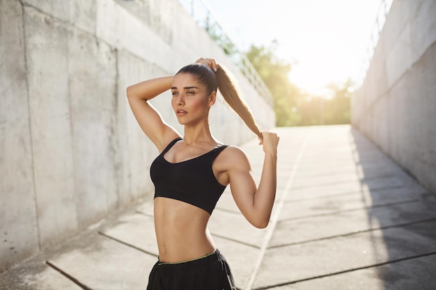 Female runner tying her hair outdoors Urban sport concept