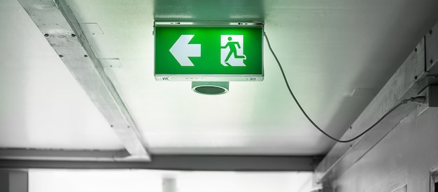 Photo fire emergency exit sign on the wall background inside building. safety concept