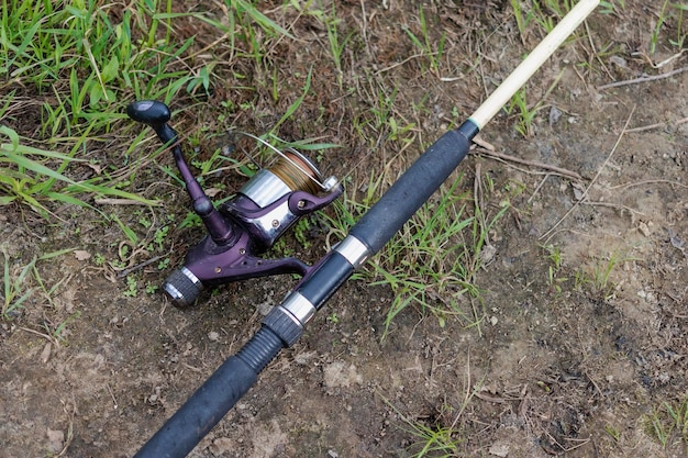 釣りスピニングは草の上にありますスピニングリールでの釣り釣り道具のクローズアップ