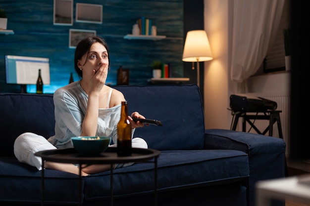 Focused interested woman eating popcorn watching interesting movie show