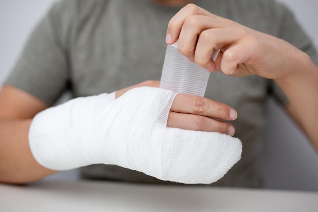 Photo fracture and first aid concept close up of man bandaging himself