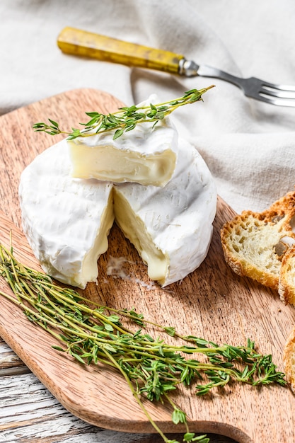 Photo french camembert cheese with grapes on wooden cutting board. white background. top view