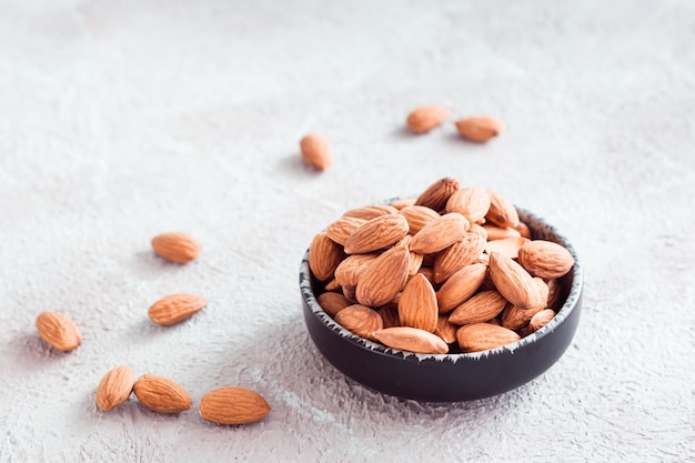 Foto mandorle fresche sbucciate in una ciotola su sfondo chiaro. una fonte di vitamine e oli. cibo organico