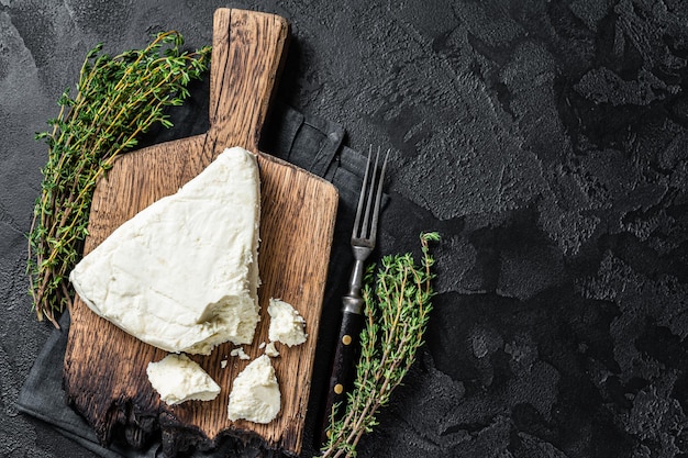 Photo fresh soft goat cheese on a cutting board with thyme black background top view copy space