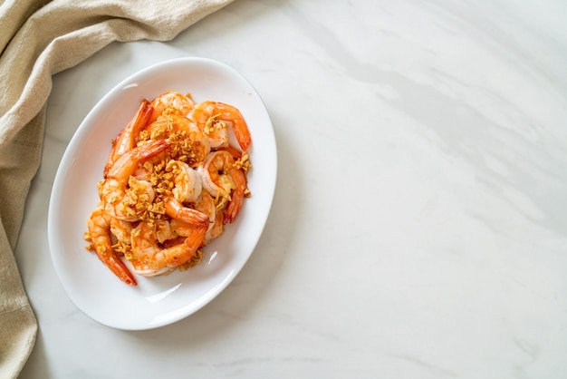 Fried shrimps or prawns with garlic on white plate - seafood style