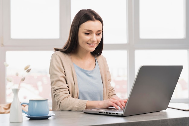 Front view of woman at desk working from home on laptop