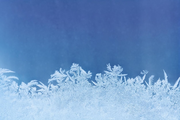 Photo frosty pattern on the deep blue window glass as background