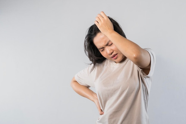 Foto una donna asiatica frustrata tiene le mani sulla testa ha mal di testa sembra infelice non riesce a gestire la pressione