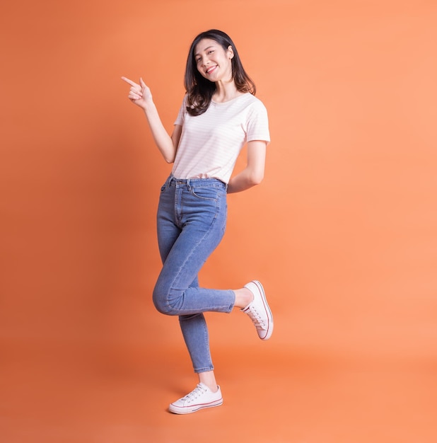 Photo full length image of young asian woman posing on orange background