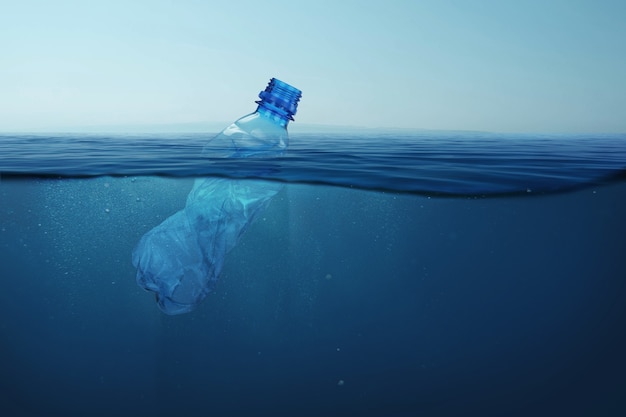 Garbage plastic bottle floats in blue sea water with underwater. Pollution of the environment and oceans.