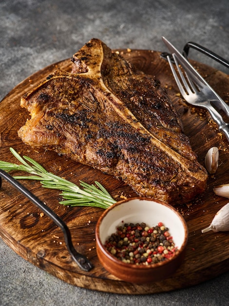 Gegrilde TBone Steak met zout en peper op snijplank op donkergrijze achtergrond Geroosterde TBone-biefstuk