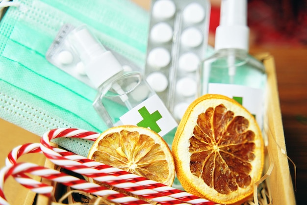 Gift box with antiseptics pills lollipops medical masks and dried oranges new years eve during pande...