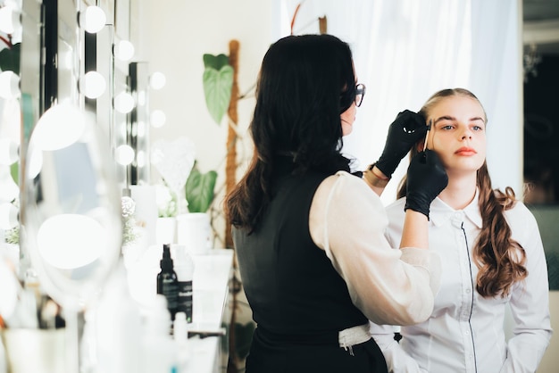 A girl in a beauty salon has an eyebrow lamination procedure, smears with white paste