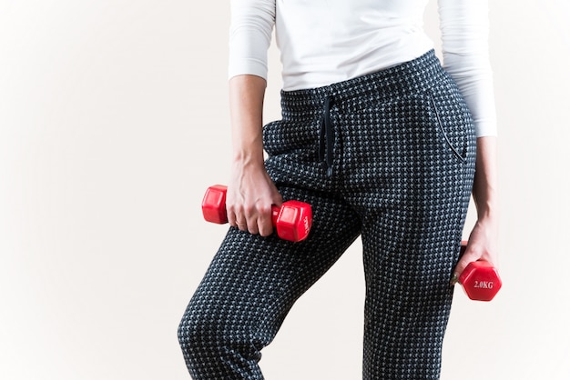 Girl in a sports suit holds a red dumbbell