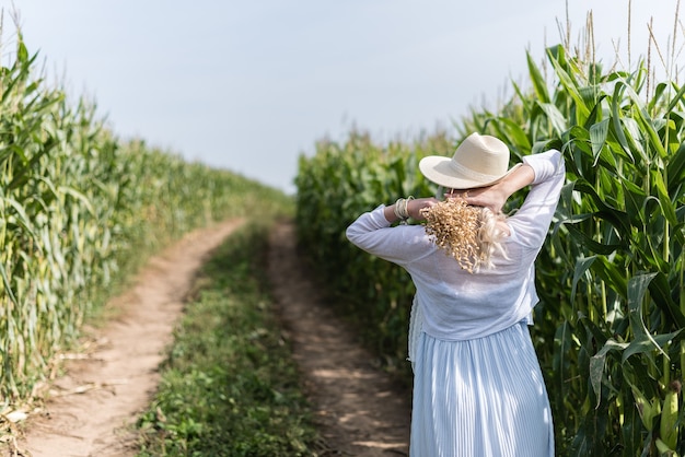 Photo a girl in a straw hat walks in the corn field