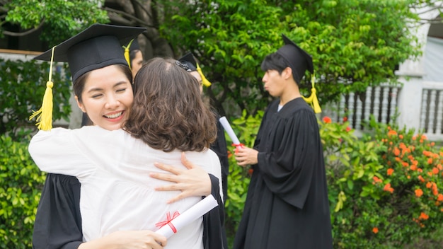 Photo girl student with the graduation gowns and hat hug the parent in congratulation ceremony.