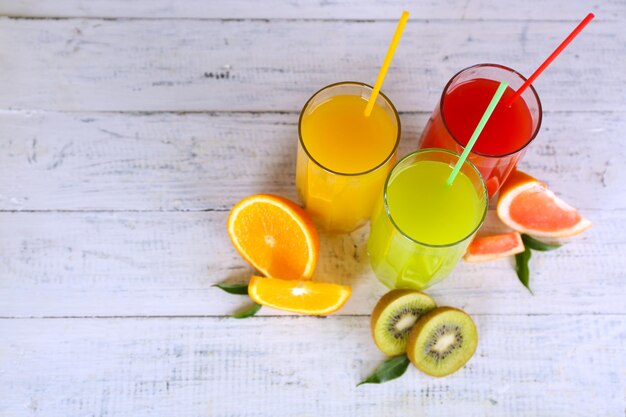 Foto bicchieri di diversi succhi con frutta e menta su sfondo di legno