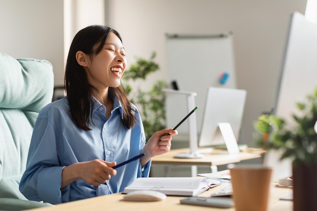 Foto glimlachende aziatische vrouw die virtuele drums speelt op het werk